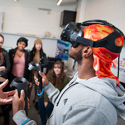 A man, wearing a VR headset, at a computer.